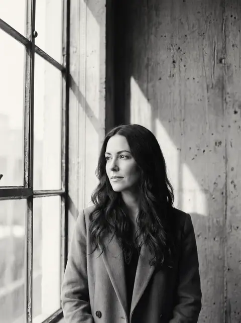 Portrait of Ingrid Solberg standing by a tall window in a concrete room